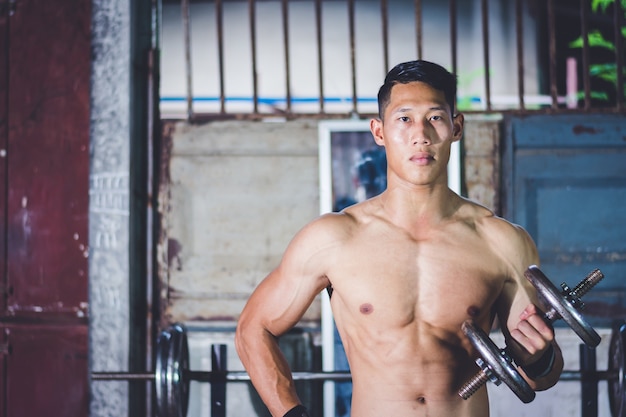 strong athletic man Doing Exercises With Dumbbells in local gym