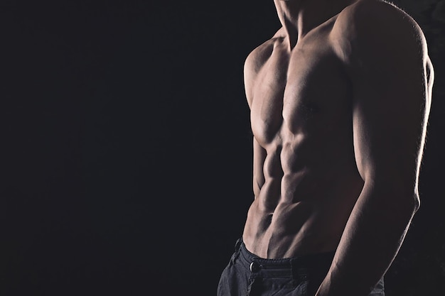 Strong athletic young man on black background