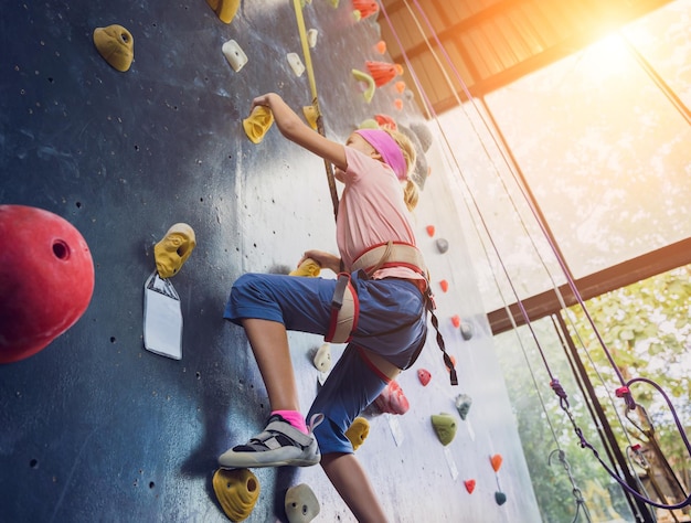 Foto un forte bambino arrampicatore si arrampica su una parete artificiale con impugnature e corde colorate