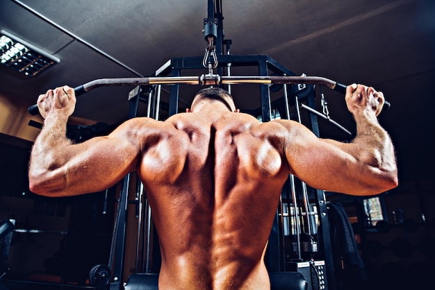 Strong bodybuilder doing exercises at the gym