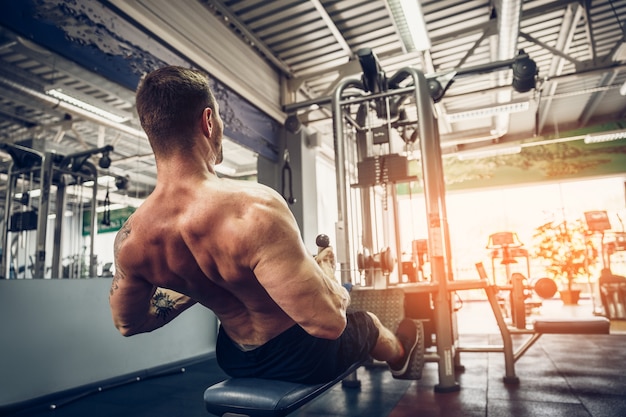 Strong Bodybuilder Doing Heavy Weight Exercise For Back On Machine