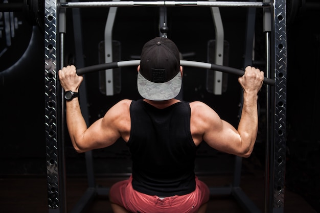 Photo strong bodybuilder doing heavy weight exercise for back on machine.