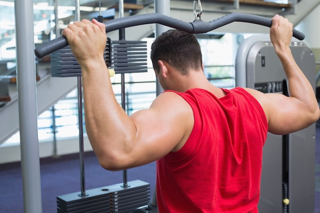 Strong bodybuilder using weight machine for arms