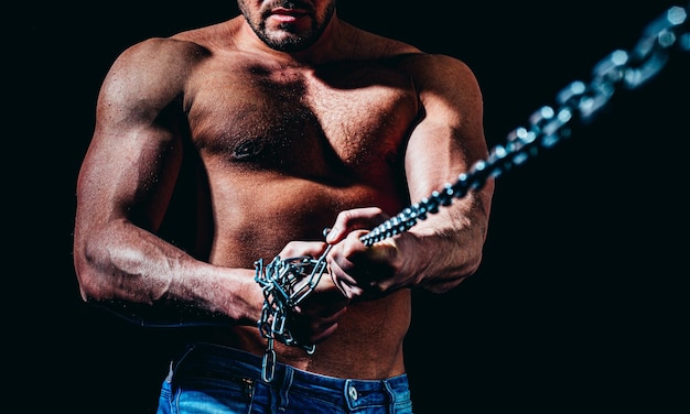 Strong bodybuilder with broken chains perfect abs shoulders biceps triceps and chest deltoid muscle Men holding chain Fitness abdominal muscle Man six pack