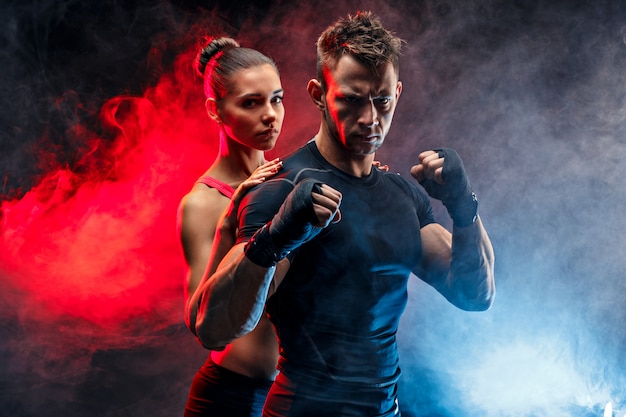 Strong boxer in stance with handwraps on his fists With girlfriend standing behind him.
