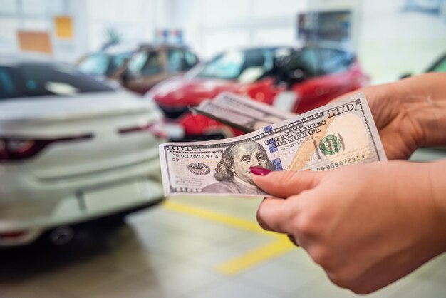 strong clean healthy hands firmly hold a round sum of dollar banknotes on the background of the car in the car. Car interior concept. The concept of buying and selling.