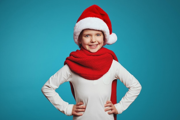 Strong confident girl in christmas hat and red scarf holding hands on waist