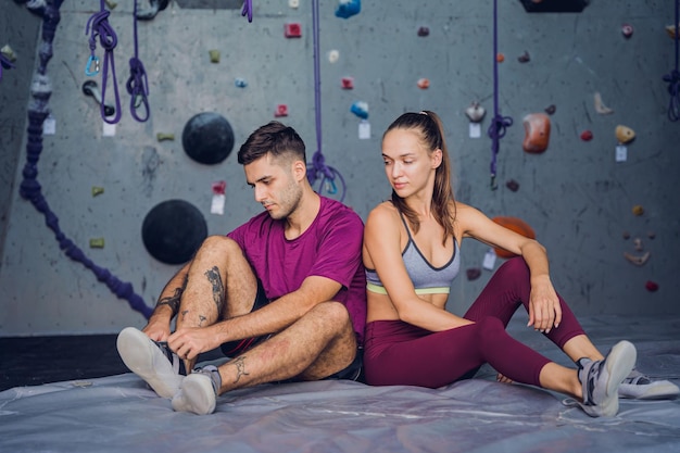 A strong couple of climbers against an artificial wall with colorful grips and ropes