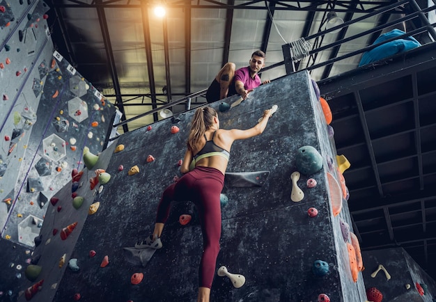 A strong couple of climbers climb an artificial wall with colorful grips and ropes