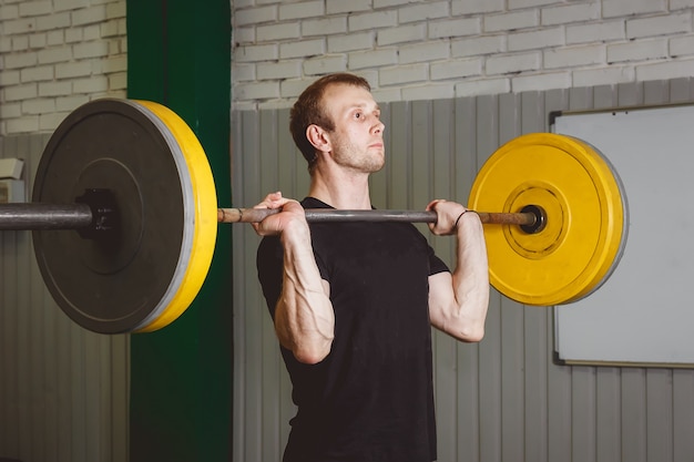 Strong crossfit athlete in a heavy overhead squat lift in a cross-fit box gym