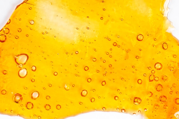 Strong extract of gold cannabis wax with high thc close up bubble shatter texture on paper