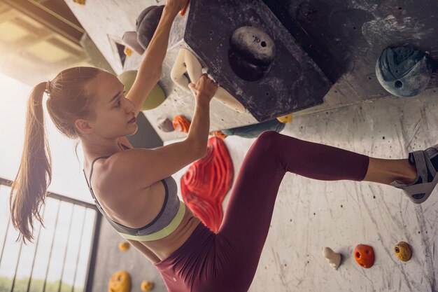 Photo a strong female climber climbs an artificial wall with colorful grips and ropes