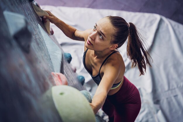 Foto una forte scalatrice si arrampica su una parete artificiale con maniglie e corde colorate