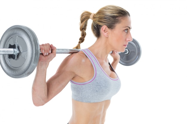 Strong female crossfitter lifting barbell behind head