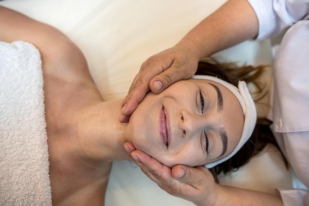 Strong female masseur is doing a cosmetology facial massage to a client spa salon concept facial skin tightening