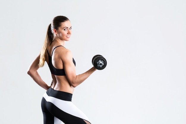 Strong fit young woman with dumbbell isolated.