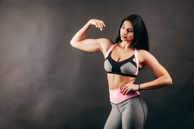 Ragazza forte fitness mostra muscoli in studio