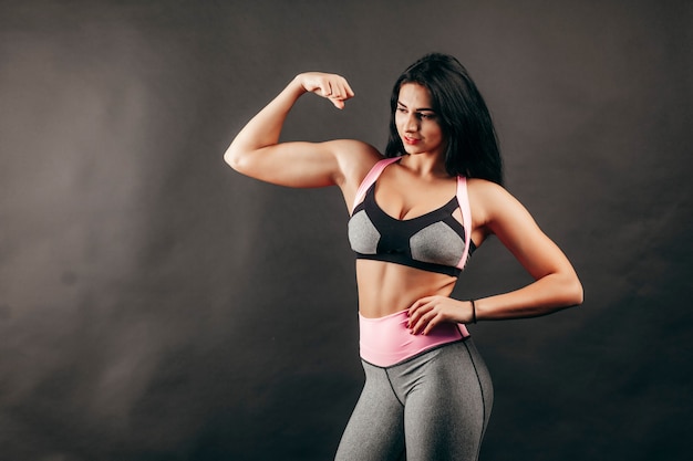 Ragazza forte fitness mostra muscoli in studio