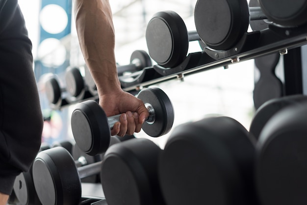 Strong fitness man posing muscular body and doing exercises for bodybuilder in the gym