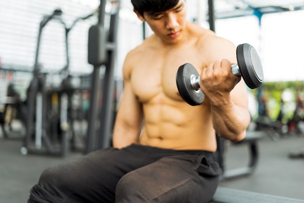 strong fitness man posing muscular body and doing exercises for bodybuilder in the gym