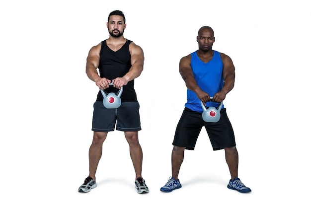 Foto amici forti che sollevano insieme i kettlebells