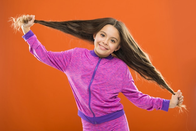 強い髪のコンセプト。子供の女の子の長い健康的な光沢のある髪。主なものはそれをきれいに保つことです。やさしいシャンプーと温水を使用してください。小さな女の子は長い髪を育てます。子供に健康的なヘアケアの習慣を教える。