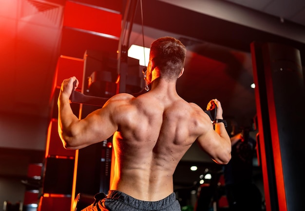 Strong handsome man training his back Bodybuilder athlete working out in gym