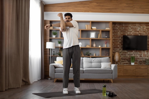 Photo strong indian man stretching arms during training at home