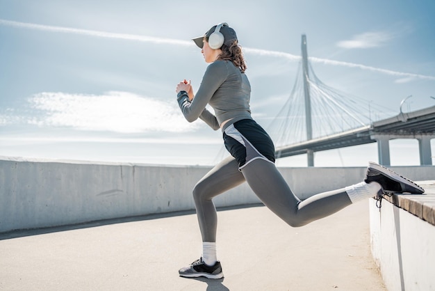 Strong legs exercise squats outdoor training a female trainer doing on the body Listens to sports