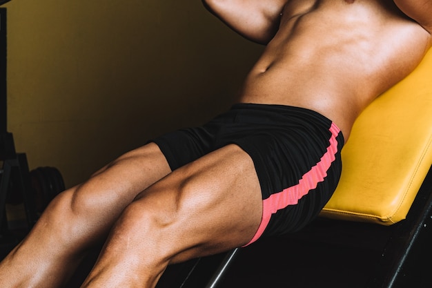 Strong legs of a man in shorts exercising in the gym