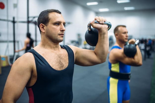 Strong male athletes with weights in gym