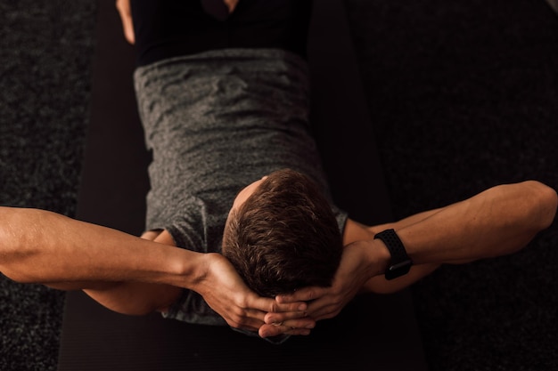 Strong male hands behind the head of an athlete who performs a\
sports exercise