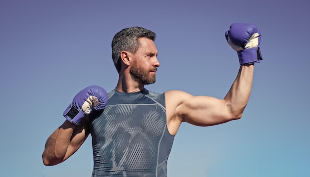 Pugile uomo forte in guantoni da boxe che mostra lo sport dei muscoli bicipiti