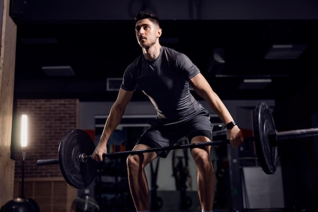 A strong man doing lifting heavy weights at the gym and exercising his biceps