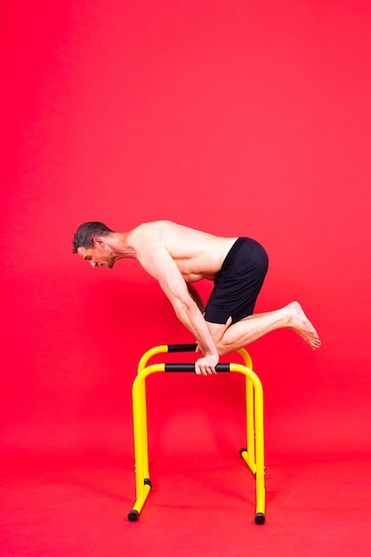 Strong man doing sports fitness on gorizontal and parallel bars pull ups on parallel bars