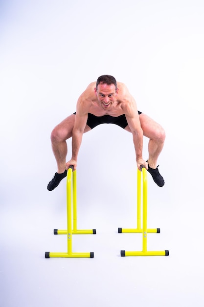 Фото Сильный мужчина занимается спортивным фитнесом на горизонтальных и параллельных брусьях, подтягивается на параллельных брусьях