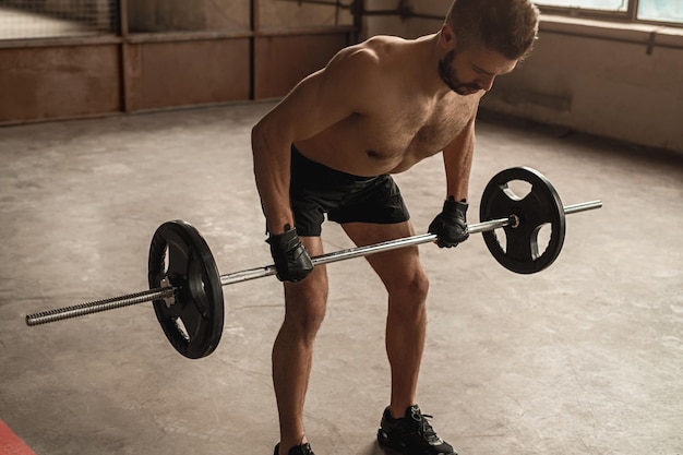 Strong man exercising with barbell in gym