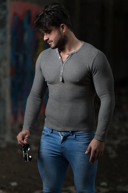 灰色のシャツの背景の落書きの壁の強い男
