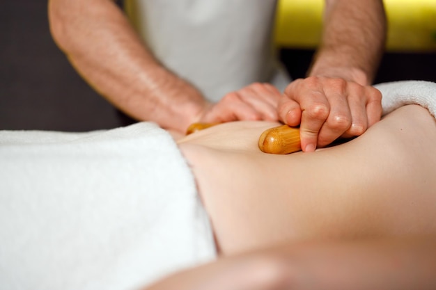 Strong man massages the patient's stomach with bamboo sticks