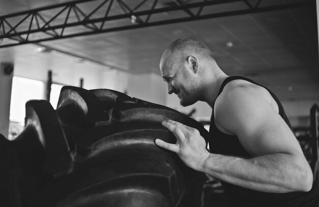 Photo strong man picks up a big heavy rubber wheel. functional training