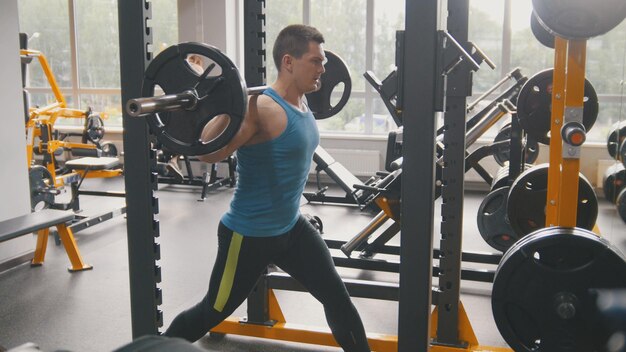 Strong man raises the bar in the gym, telephoto shot