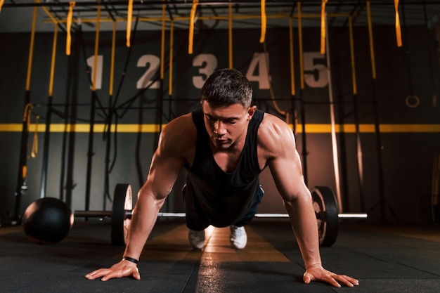 Strong man in sportive clothes doing pushups in the gym