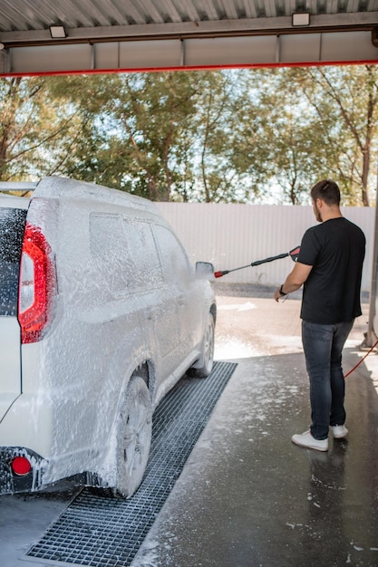 Strong man washing car at self carwash outdoors