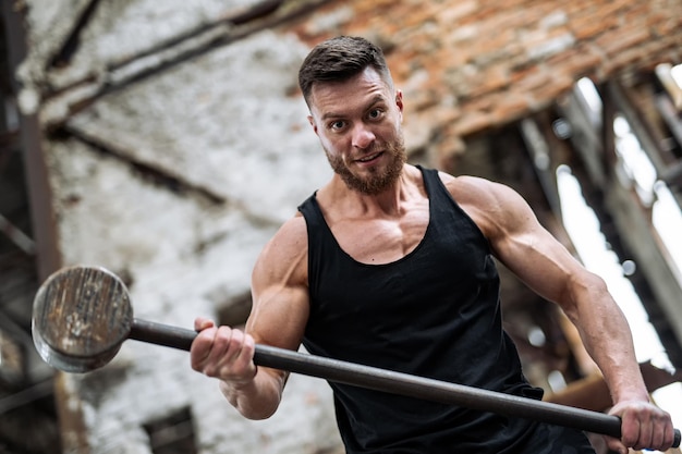 Strong man with strong hammer Handsome powerful young bodybuilder