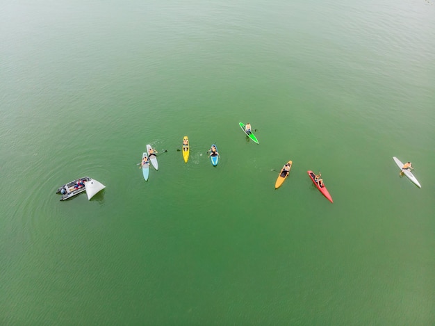 Strong men floating on a SUP boards in a beautiful bay on a sunny day Aerial view of the men crosses the bay using the paddleboard Water sports competitions