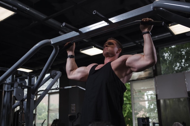 Photo strong muscular man doing pull ups at the gym