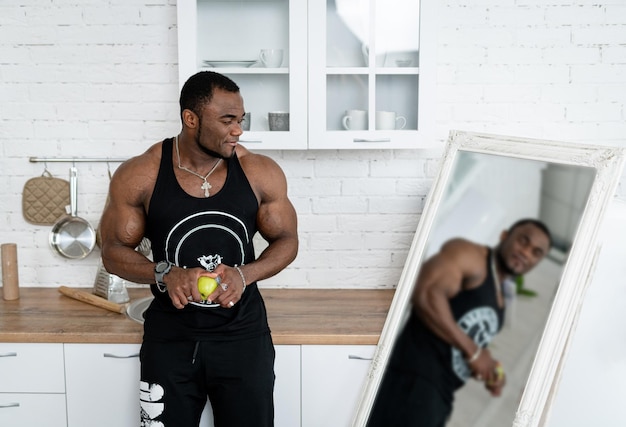 Strong muscular man standing by the mirror Attractive young bodybuilder