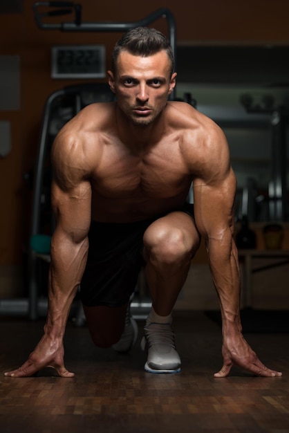 Фото Сильные мускулистые мужчины стоят на коленях на полу почти как спринтер.