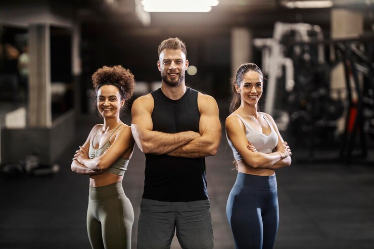 Photo strong muscular sportspeople standing in a gym with arms crossed and smiling at the camera