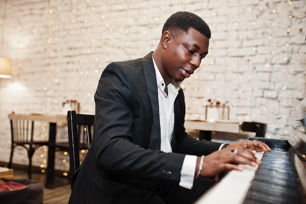 Strong powerful african american man in black suit play piano